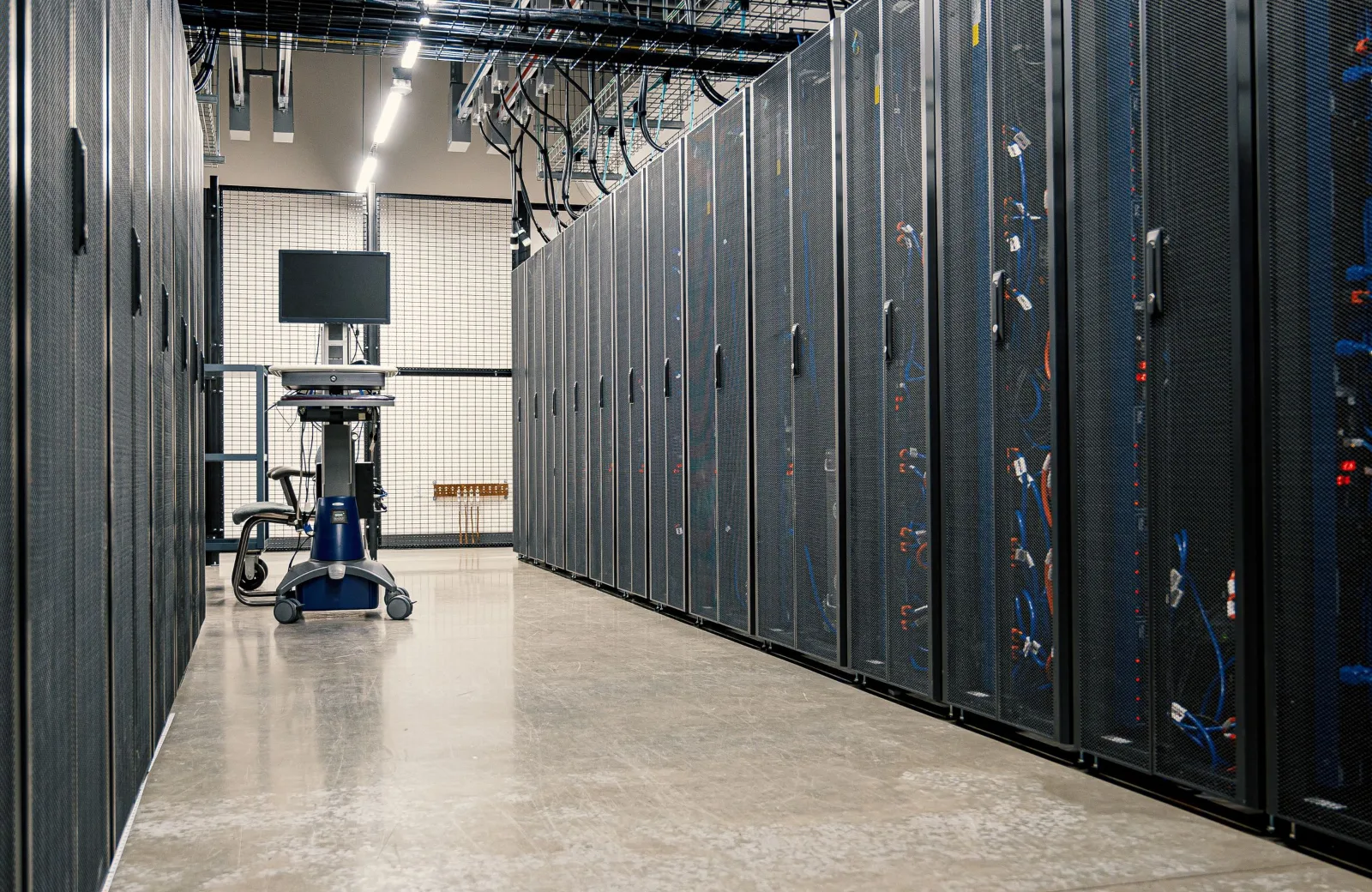 Rows of server racks in a data center with a maintenance workstation, representing WordPress hosting and ongoing maintenance